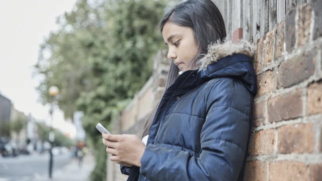 Girl with phone against wall