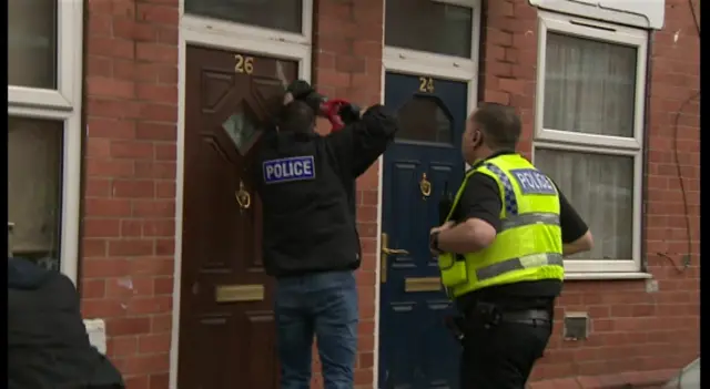 Police officers force entry to a terraced house