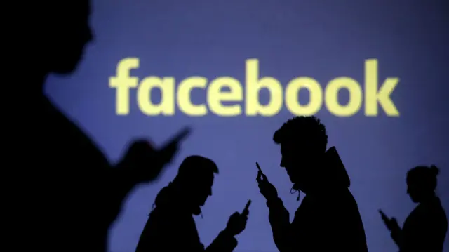 Silhouettes of mobile users in front of a Facebook logo