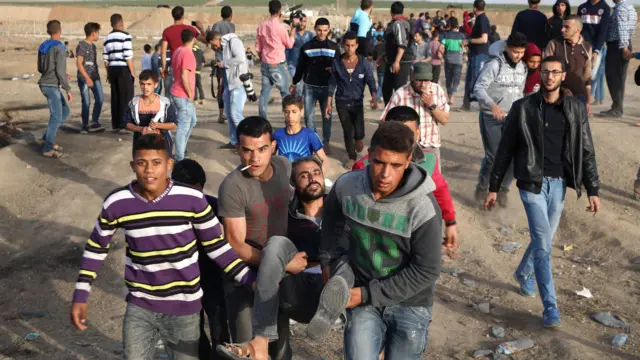 Palestinian youths carry a wounded man during clashes with Israeli forces