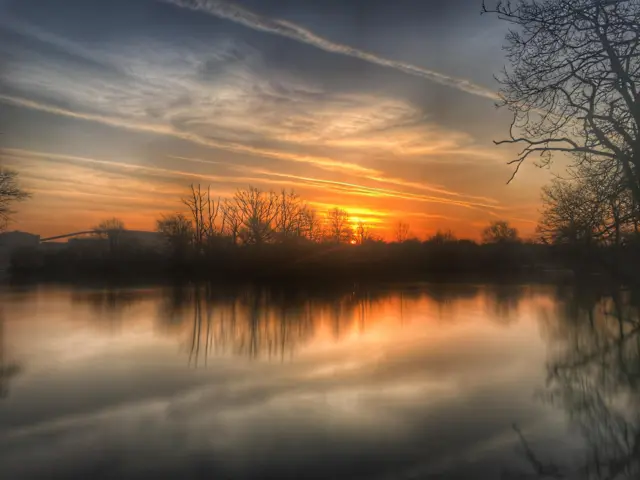 Orange sky with wispy clouds over a lake