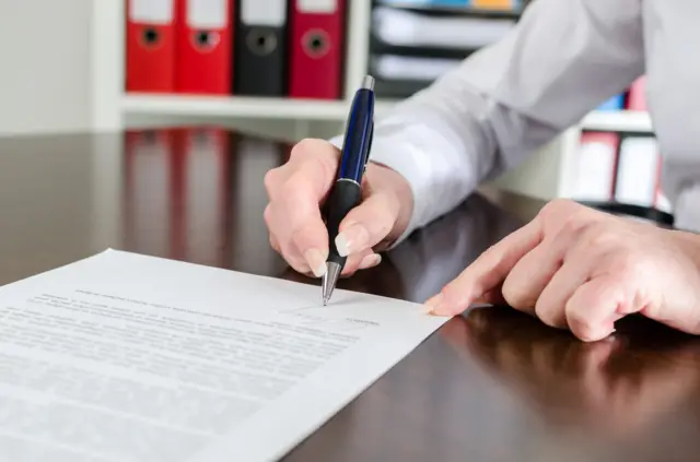 A woman signing a letter