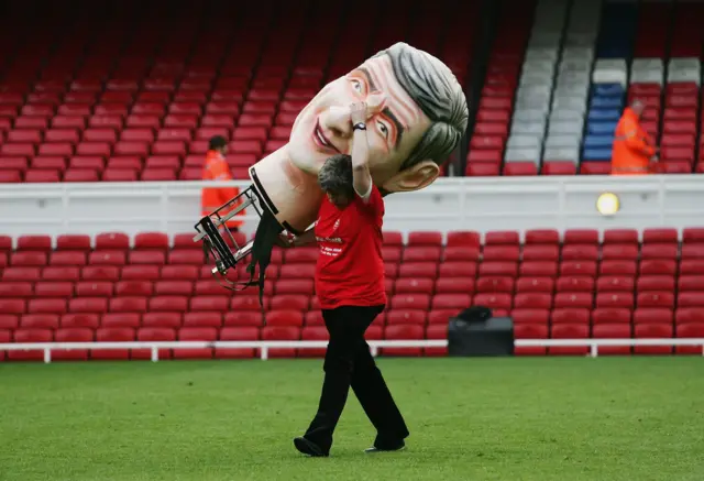 A stadium worker holding part of an Arsene Wenger statue