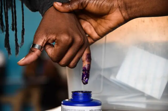 A voter dips his finger in ink after casting his vote at a polling station in Freetown on March 31, 2018 during the final round of a delayed run-off presidential election