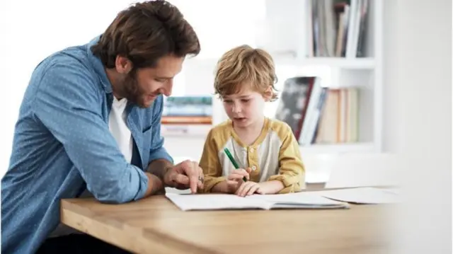 man working with child at a table