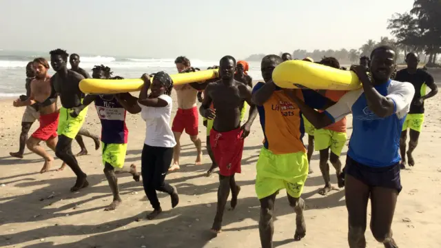 lifesavers running on beach with lifeguard rescue boards