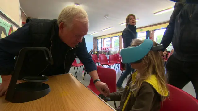 older man on left, young girl wearing virtual reality headset on right