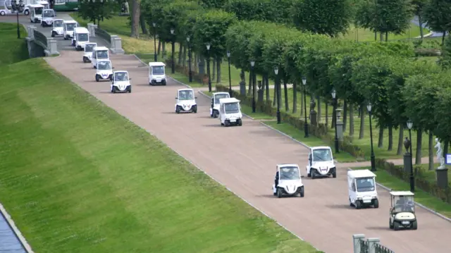 Generic photo of line of golf buggies in use