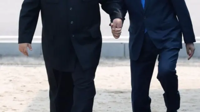 Moon and Kim hold hands as they walk over the border