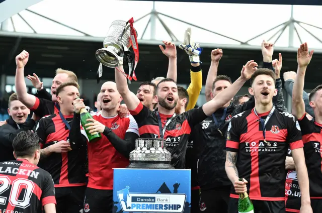 Crusaders captain Colin Coates lifts the Gibson Cup after winning the Premiership title