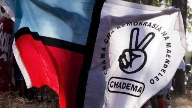 A supporter of the opposition Chadema party poses with an opposition flag as he wait for the results of the general elections outside a polling station in Dar es Salaam on October 27, 2015