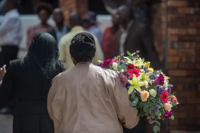 Women bring flowers to pay tribute to late South African anti-apartheid campaigner Winnie Madikizela-Mandela, wife of African National Congress (ANC) leader Nelson Mandela at her Olando Soweto house, on the outskirts of Johannesburg on April 3, 2018