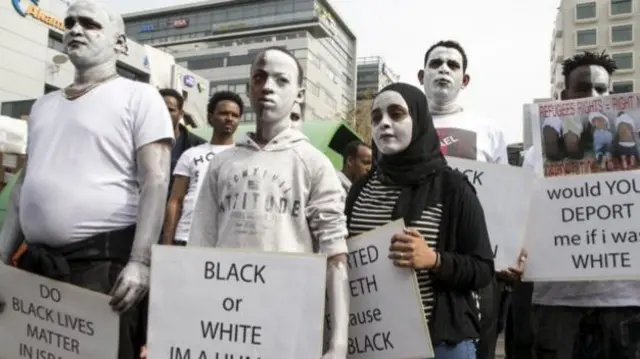 Protesters with their faces painted white