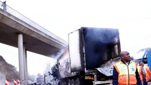 Officials near a burnt-out truck on the N3, South Africa