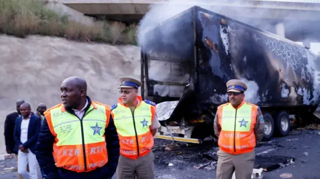 Officials near a burnt-out truck on the N3, South Africa