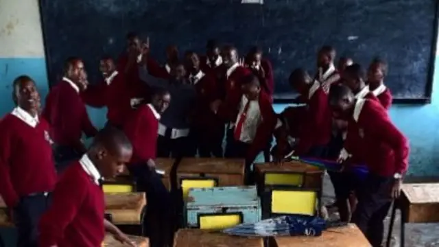 Kenyan school children tryto bail out water from their classroom at Isinya Secondary School at Isinya