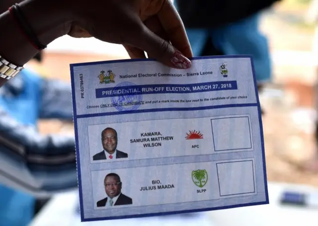 A voter shows a ballot paper at a polling station in Freetown on March 31, 2018 during general elections