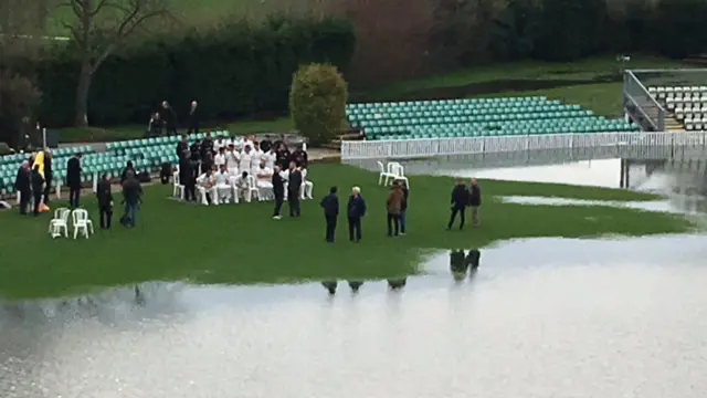 Team photo on a patch of grass beside the flood water