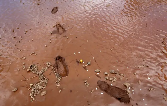 Footprints are seen on wet ground as volunteers arrive for a recovery mission after a dam burst, which unleashed water at nearby homes, in Solio town near Nakuru, Kenya