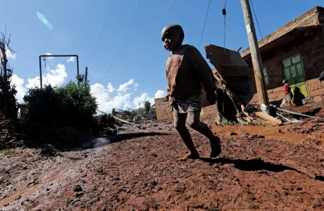 A child walks near destroyed houses by flooding water after a dam burst, in Solio town near Nakuru, Kenya May 10, 2018