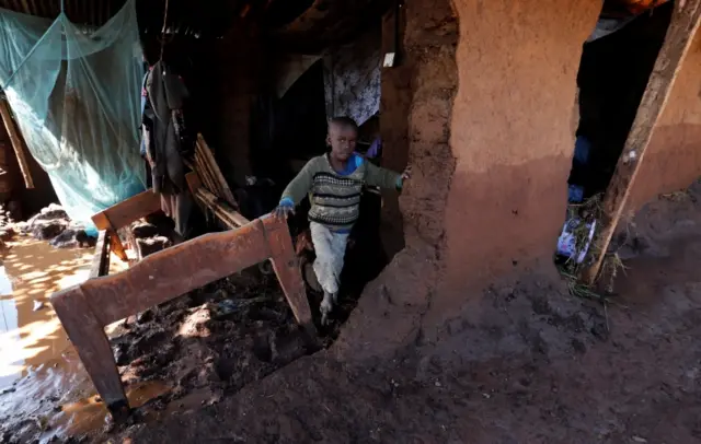 A child walks in his house, which was partly destroyed by flooding water after a dam burst, in Solio town near Nakuru,