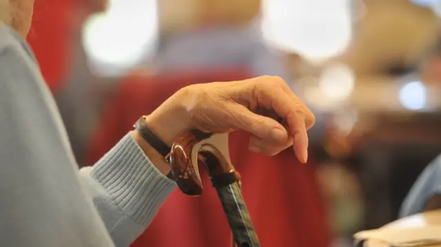 Close up of a woman's hand and walking stick