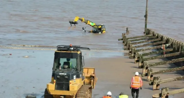 Workers looking at the stranded JCB.