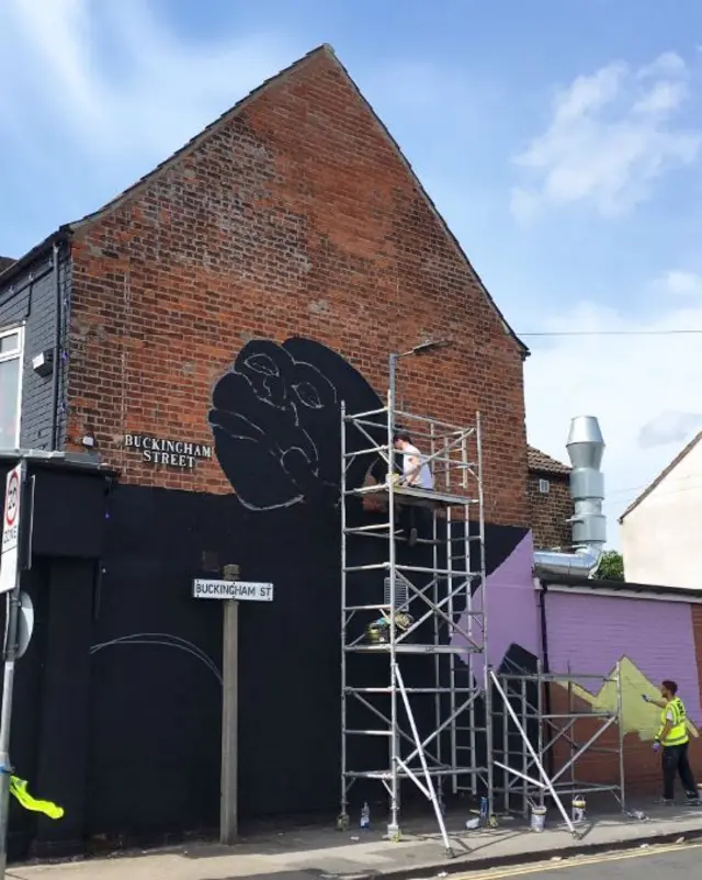 The gable end of a house being painted. You can see the face of a gorilla being painted.