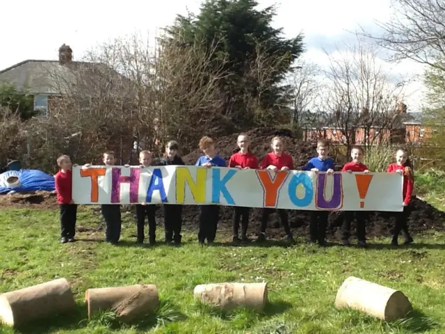 Children holding a banner, which reads "thank you"