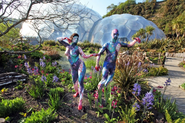 two painted human models in front of biomes