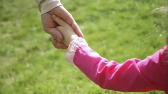 Adult holding child's hand