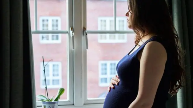 Pregnant woman looking out a window