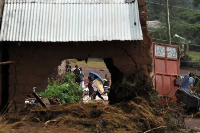 Villagers walk past a building on May 11, 2018 destroyed by floods after a dam burst its banks, sending muddy waters raging through homes and killing at least 45 people in Subukia, Nakuru county.