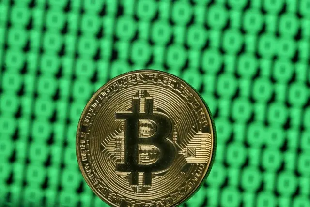 A token of the virtual currency Bitcoin is seen placed on a monitor that displays binary digits in this illustration picture, December 8, 2017