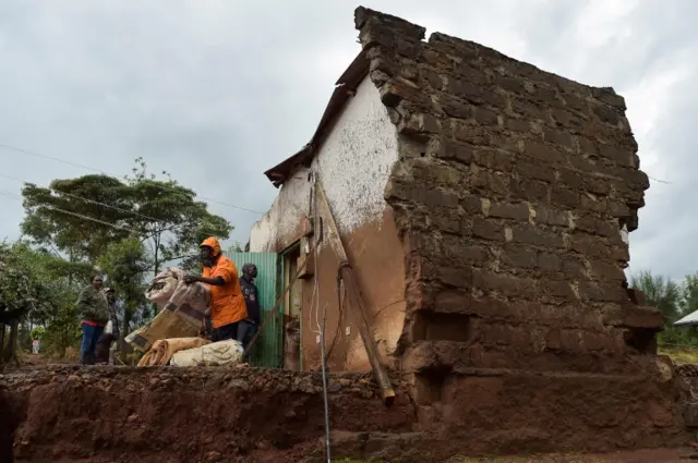 Residents try to save seeds from a granary building destroyed by floods on May 11, 2018 after a dam burst its banks