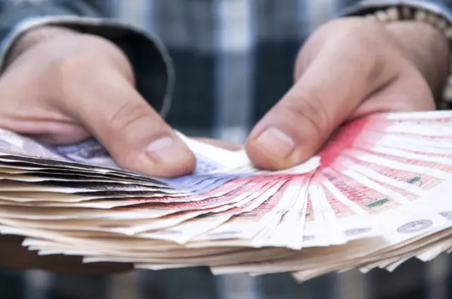 A man holding sterling banknotes