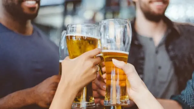 Group of friends toasting with beer glasses in the pub.