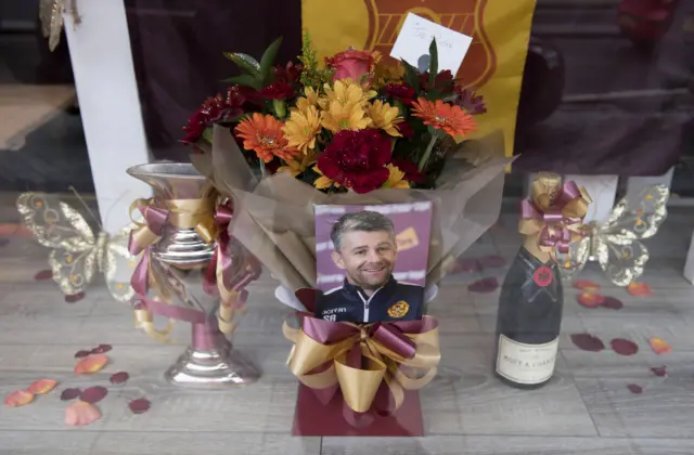 Display showing Motherwell boss Stephen Robinson, flowers and champagne