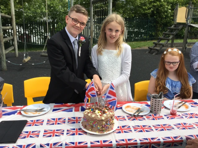 two children cutting a cake