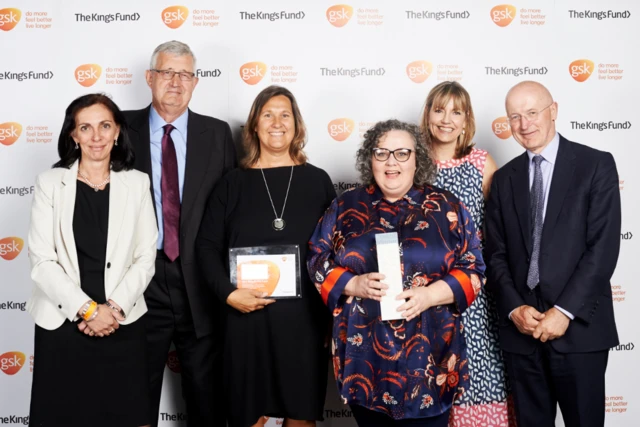 Six people posing, two holding awards