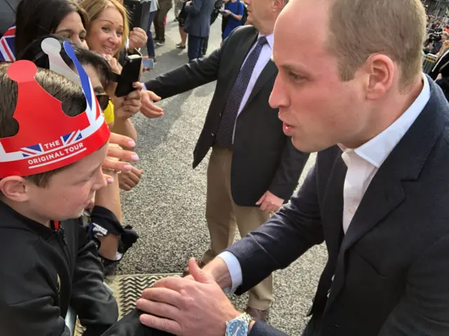 Prince William kneeling to talk to William, who wears a cardboard crown