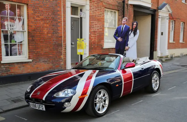 Cardboard cut outs of Harry and Meghan standing in a union jack convertible