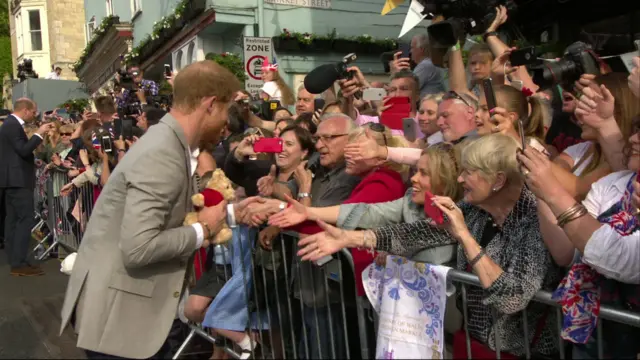 Prince Harry holds a teddy bear given to him by a member of the crowd