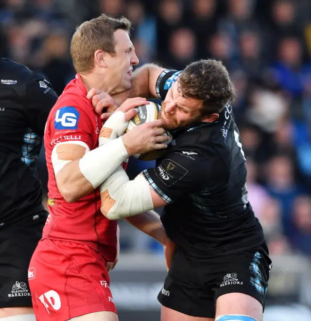 Glasgow Warriors' Callum Gibbins competes with Scarlets' Hadleigh Parkes (left)