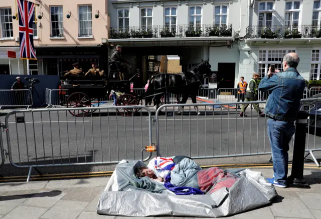 Someone sleeping beside barriers, covered in a union flag