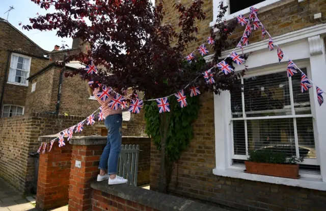 A woman hangs bunting from their house