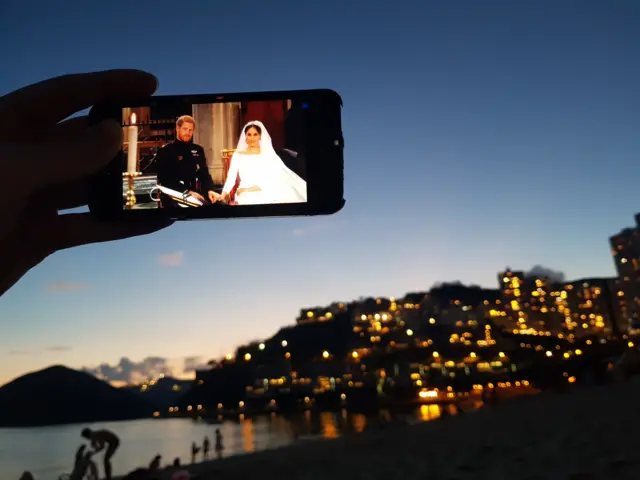 Harry and Meghan being watched on a smartphone on Repulse Bay beach in Hong Kong