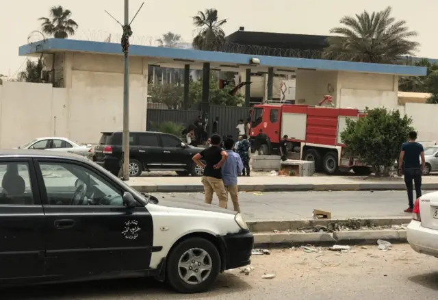 A picture taken on May 2, 2018 shows people gathering outside the Libyan electoral commission headquarters in the capital Tripoli after it was targeted by a suicide attack