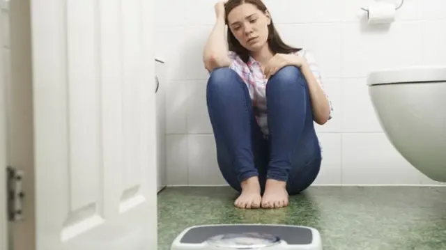 Woman in bathroom near scales