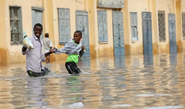 Residents wade through a flooded street in the Hamerweyne district of Mogadishu, Somalia